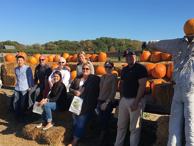UMass Chan Employees visit the apple orchard. Pumpkins in background.
