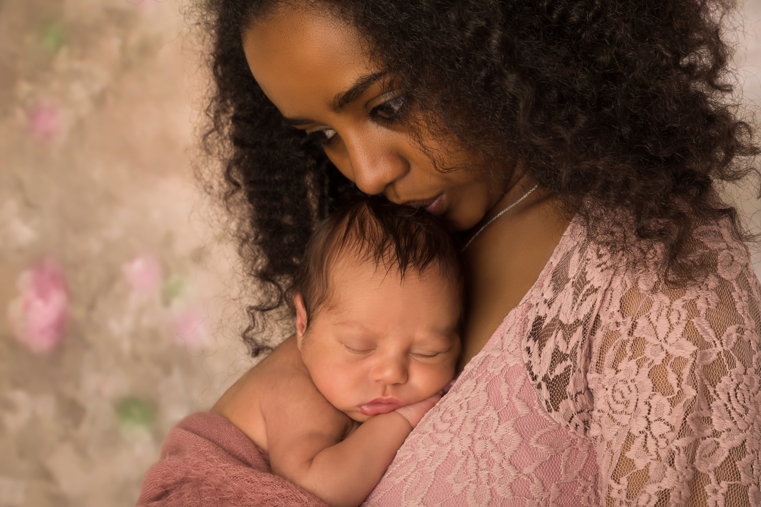 black mother holding sleeping infant and looking concerned
