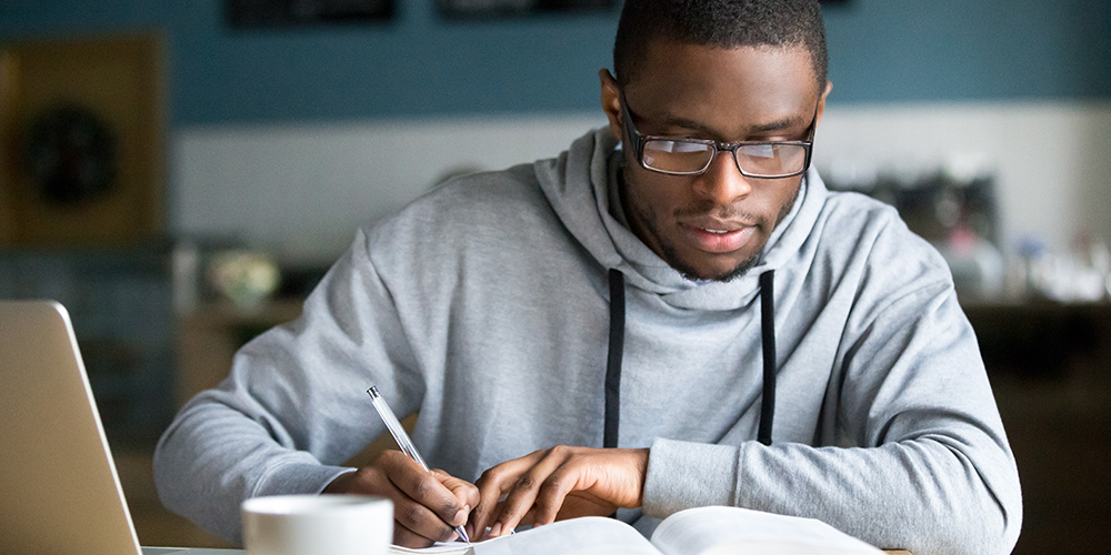 black male teen studying with notebook