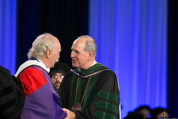 Honorary degree recipient Dermot Desmond is recognized by Chancellor Collins.