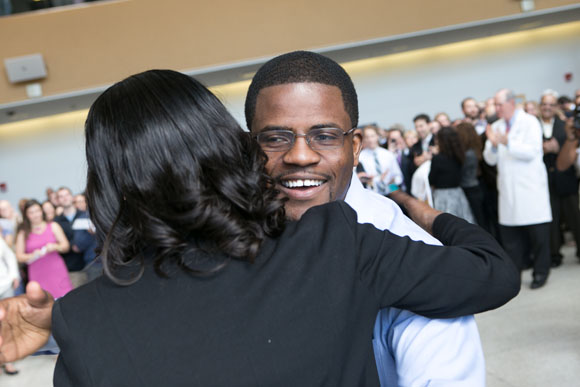 Josiah Bote, SOM ’16, (right), is congratulated by Kathy Alvarez after picking up his envelope.