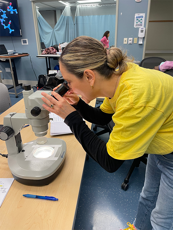 a picture of a woman looking excitedly into the eyepiece of a microscope