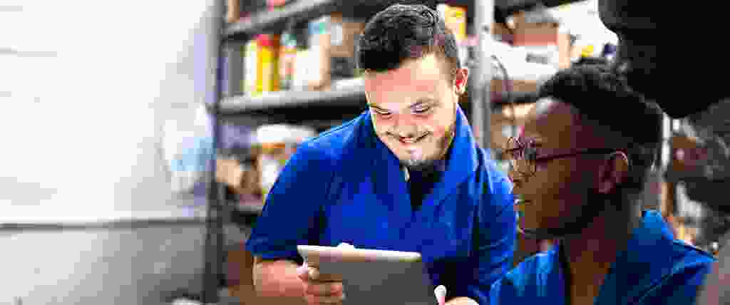 Disabled worker looking at tablet with other colleagues in vocational setting