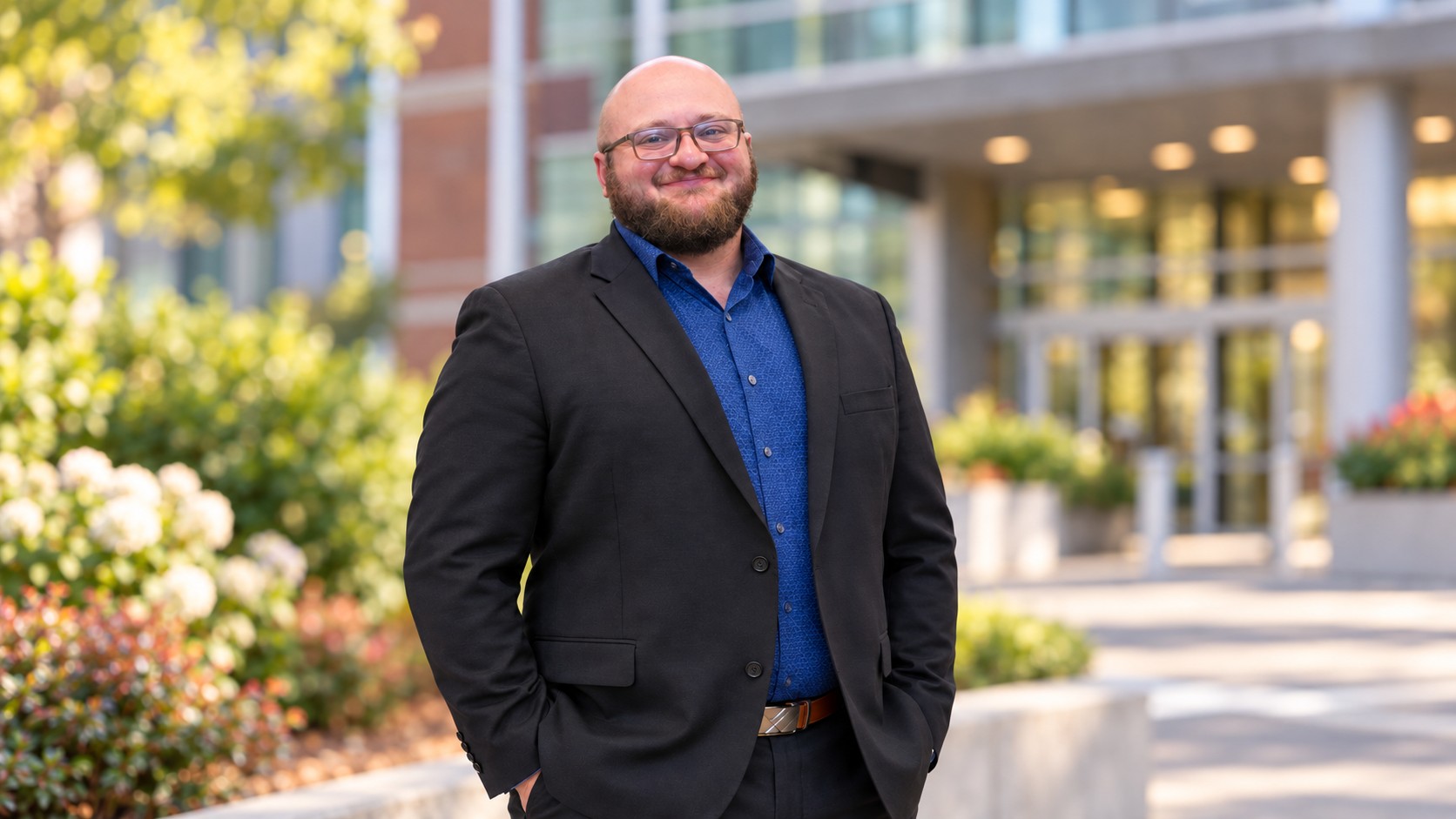 Nate standing outside of a buidling wearing a suit