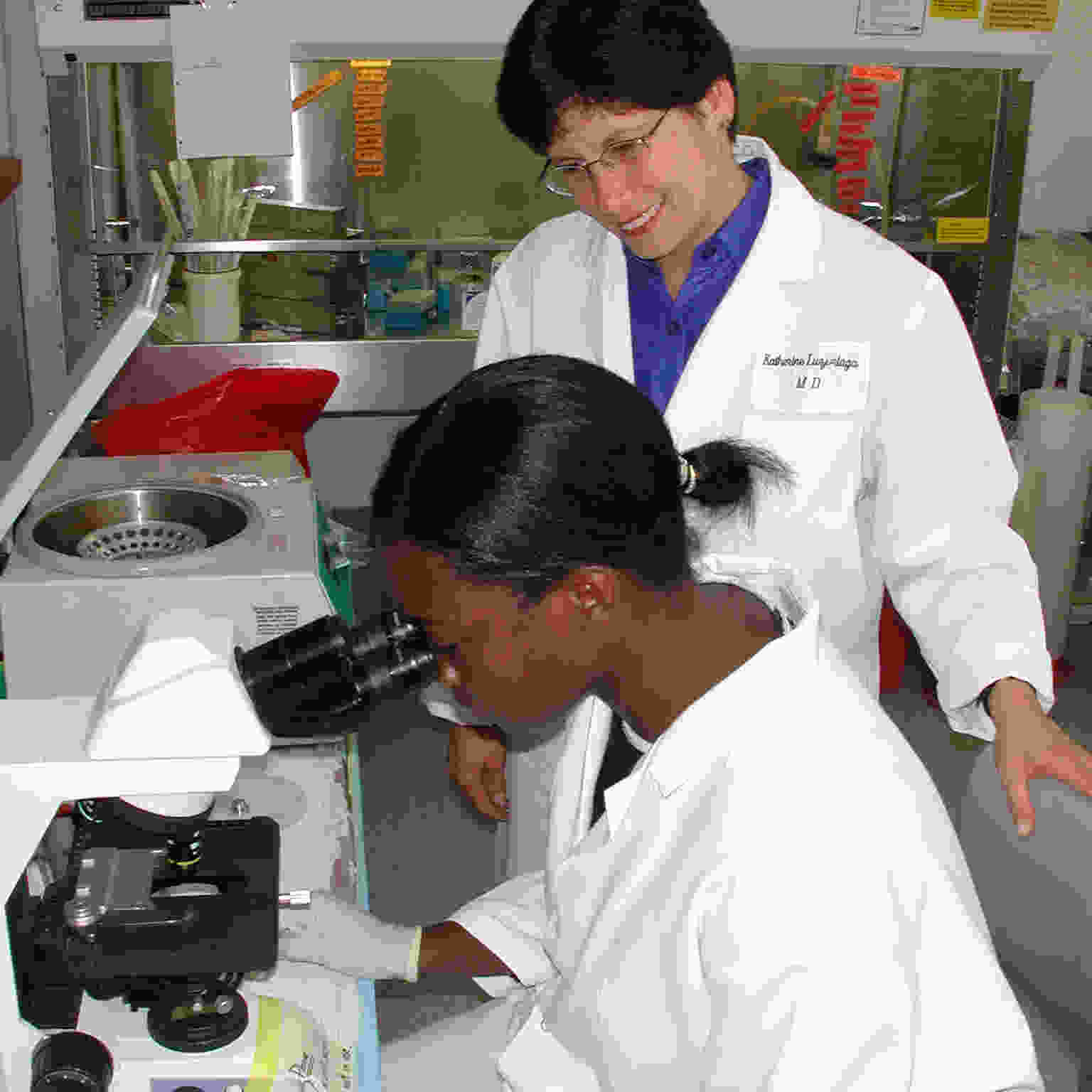 Why It Matters - 2 researchers at UMass, one standing while the other looks through microscope