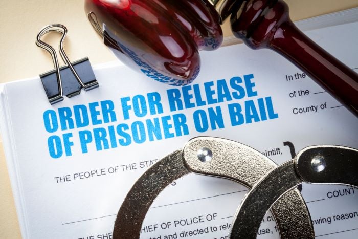 handcuffs and judges mallet on top of bail paperwork