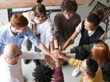 group of diverse people standing in circle with arms out and hands connected to each other