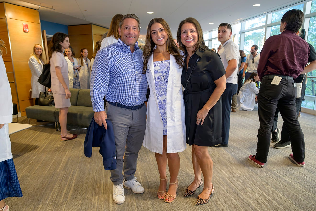DNP student Amanda Berry poses for a photo in her white coat with her parents following the transition into clinical practice ceremony at UMass Chan