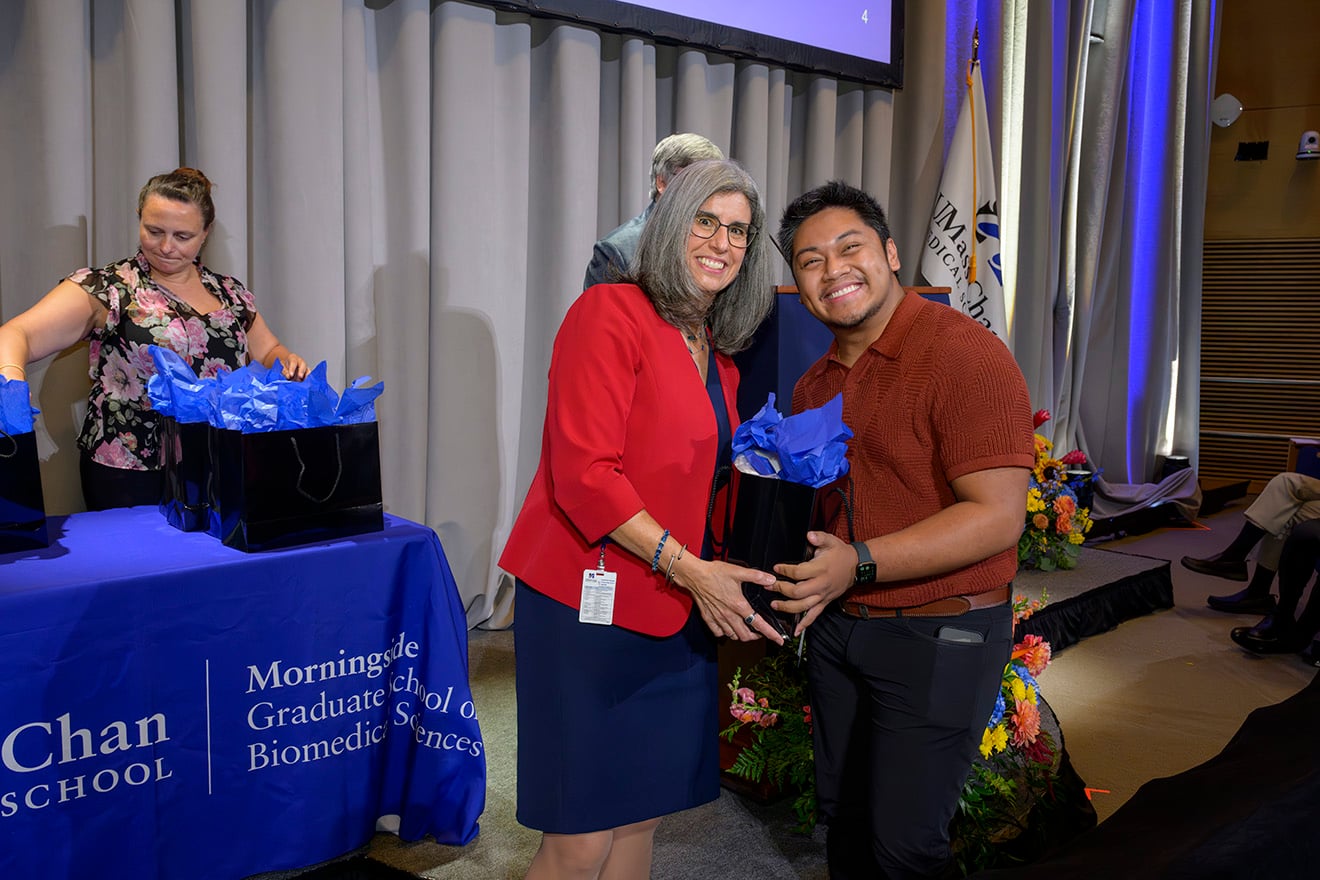 PhD candidate Josh Velasco received a bag containing his lab coat and a fleece jacket from Dean Mary Ellen Lane, PhD.