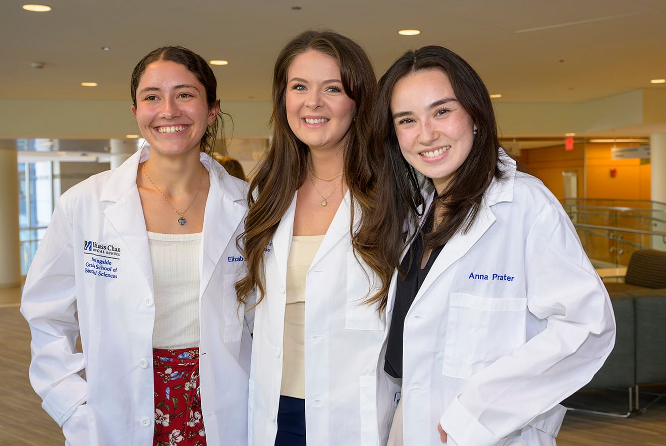 PhD candidates Elizabeth Rucki, Mary Capps and Anna Prater sport their new lab coats, handed out in gift bags at the Qualifying Exam Recognition Ceremony.