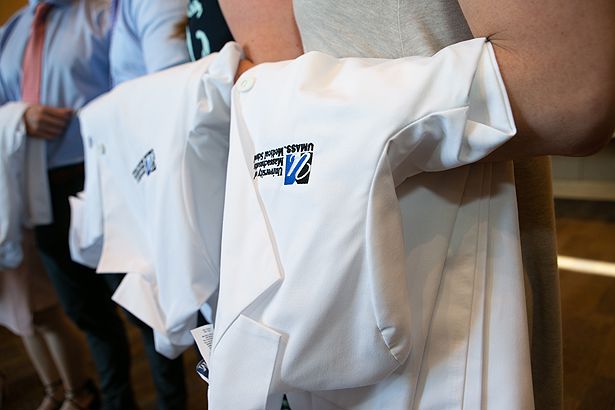 Each student carries the white coat they will don during the ceremony.