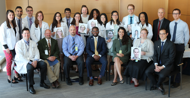 2018 Gold Humanism Honor Society inductees, nominated for their focus on patient-centered care, are pictured here with chapter advisor Michael Ennis (standing second from right). New inductees who were unable to attend are represented by the photographs that several students are holding.