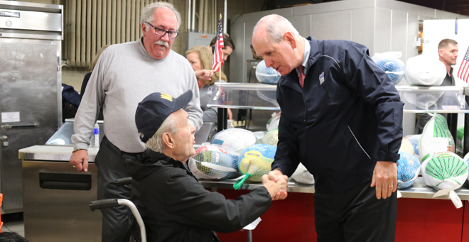 Chancellor Michael F. Collins shakes hands with a veteran at the Holiday Harvest event at Veterans Inc. on Nov. 20.