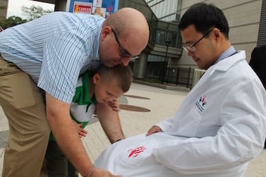 Kenneth Laferriere helps his son, Kaiden, put a red handprint on the pocket of the new Hyundai Hope on Wheels lab coat given to grant awardee Wen Xue, PhD.