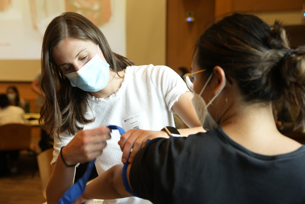 Sara Buscher (left) puts a tourniquet on fellow first-year medical student Minhtam Tran during the Stop the Bleed exercise.