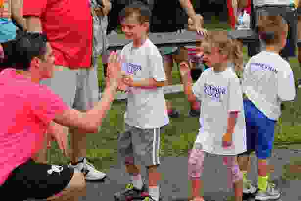 Gov. Cellucci's grandchildren, Rhys and Francesca Adams, and Gabriel Westberg, celebrate with runners at the finish line.