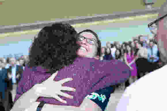 Julia Randall, SOM ’16, (right) gets a hug from Diane Blake, MD, after picking up her envelope.