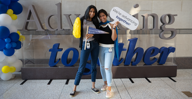 Medical students Sahana Bail and Karen Ghobrial pose in front of letters that spell out Advancing Together.