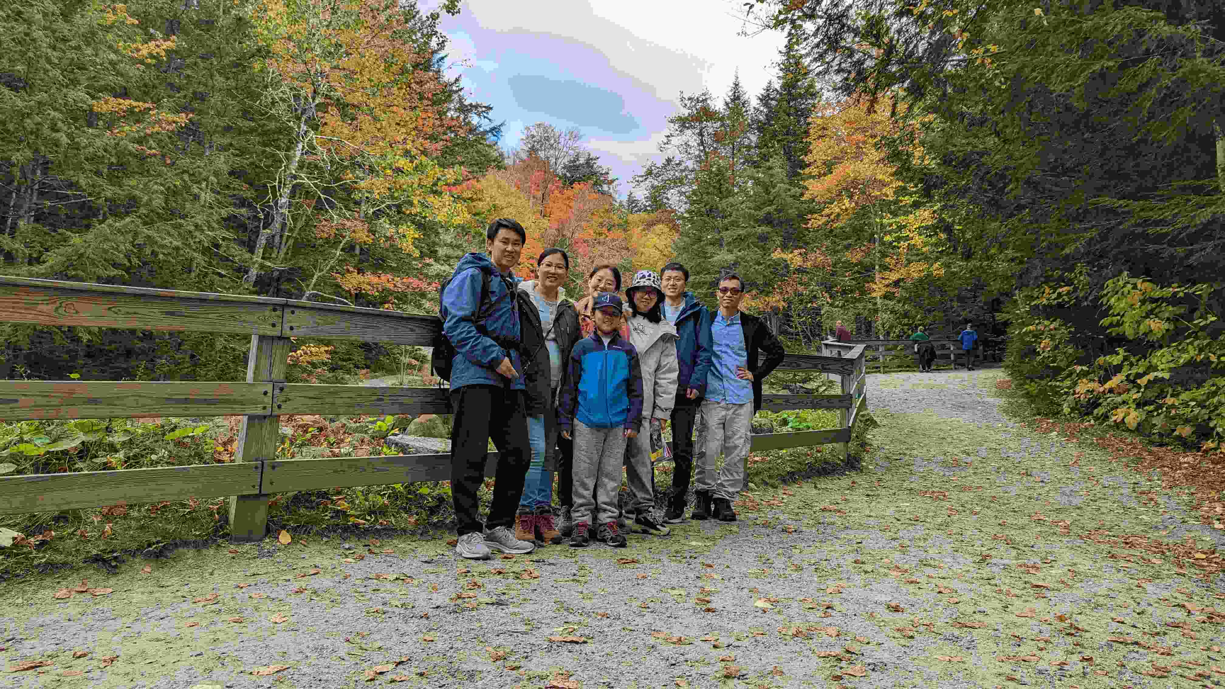 Six people stand in front of fall foliage, smiling for a group photo.