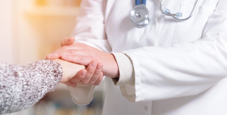 Closeup of female doctor holding patient hand