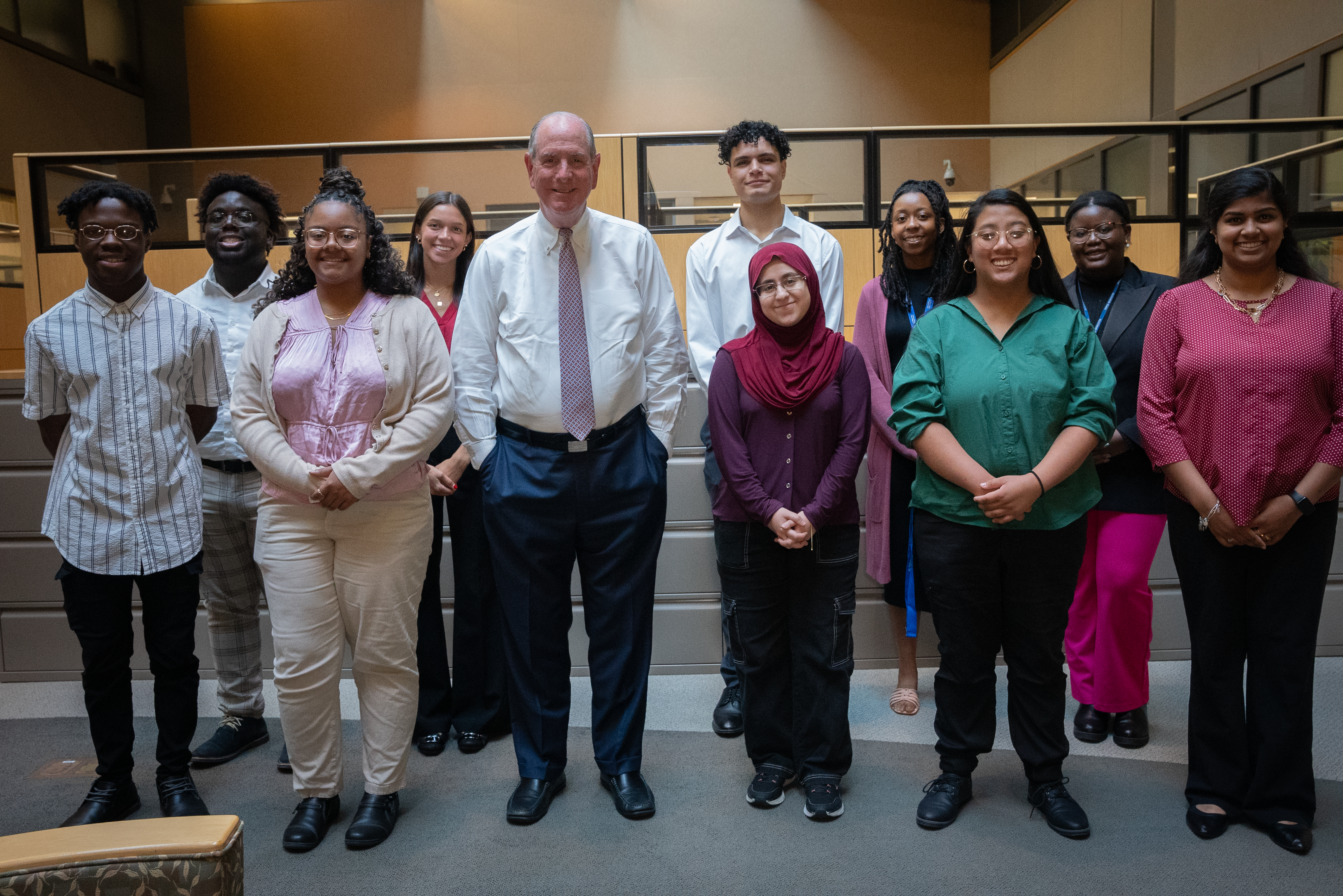 Students standing with Chancellor Collins inside a conference room