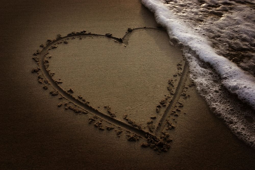 heart drawn in the sand at the beach