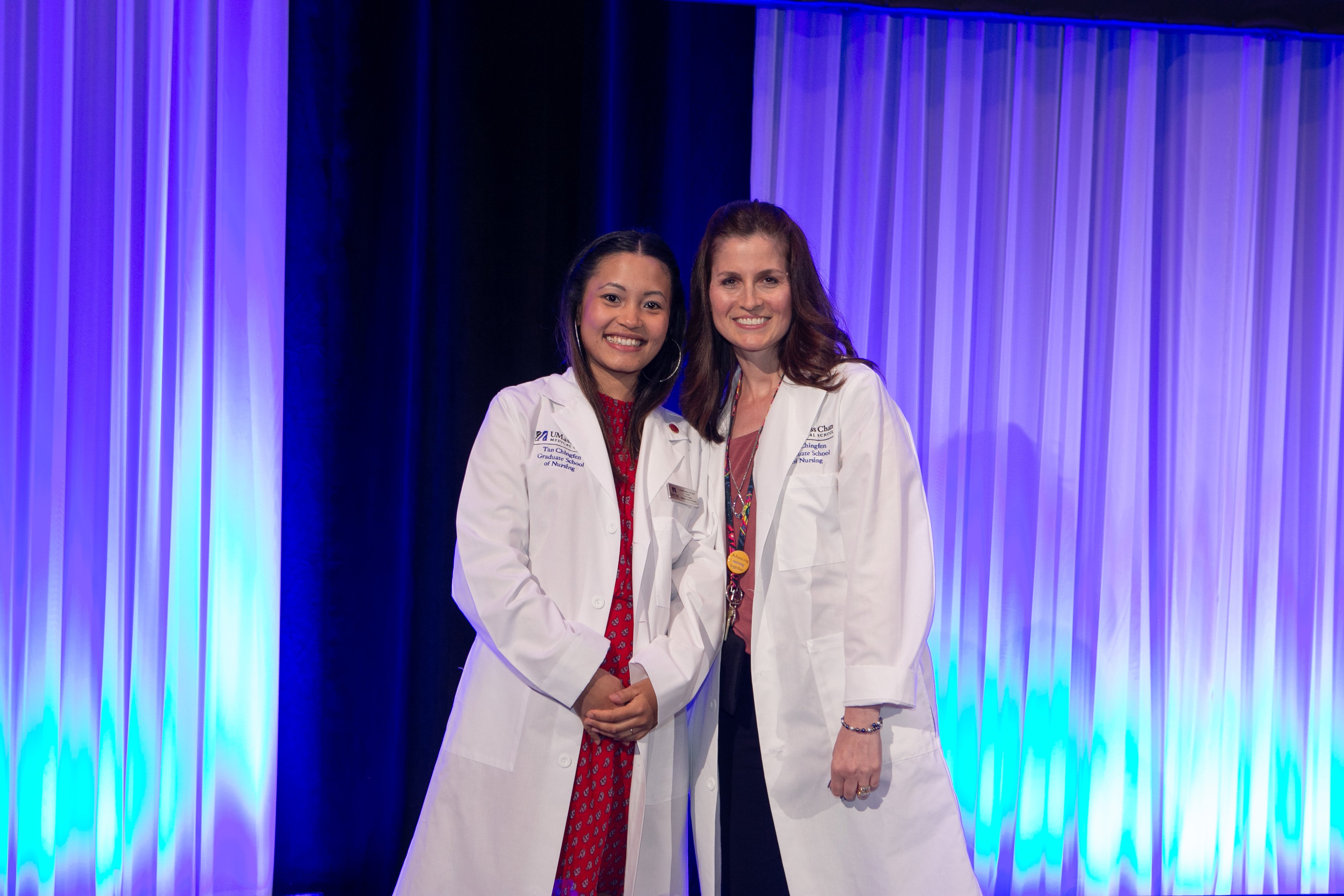 Two students on stage wearing white coats